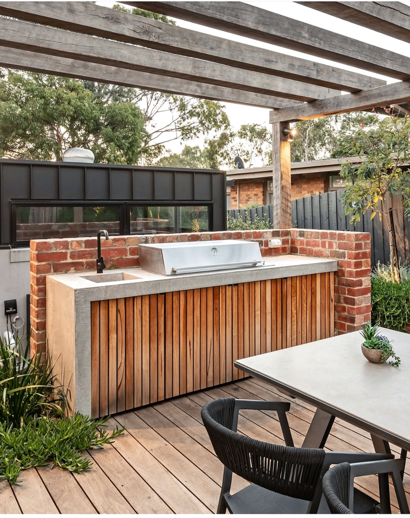 Outdoor kitchen with timber slat cabinetry, concrete benchtop and pergola by Cape Build